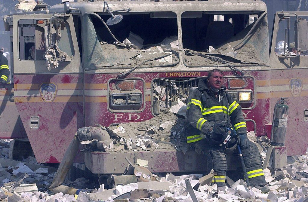 Ein erschöpfter Feuerwehrmann sitzt auf einem demolierten Feuerwehrauto